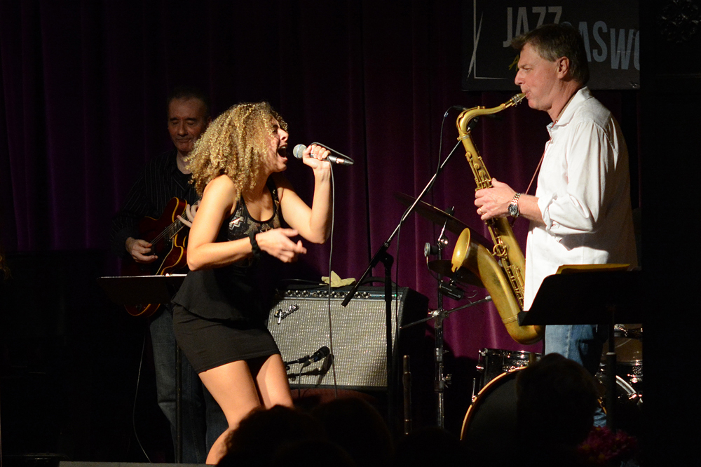 Hailee Rose sings into microphone next to Darcy Hepner playing saxophone